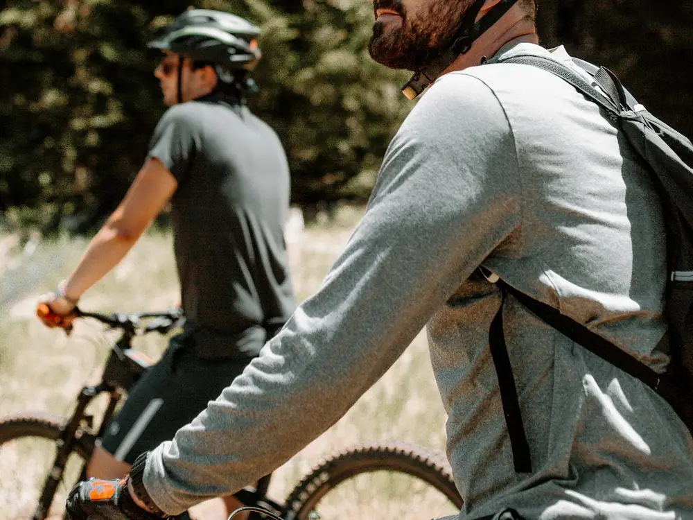 Two cyclists wearing helmets and sunglasses pausing during a ride